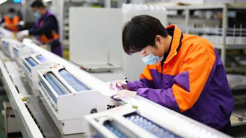 Workers in a factory setting assembling electronic components.